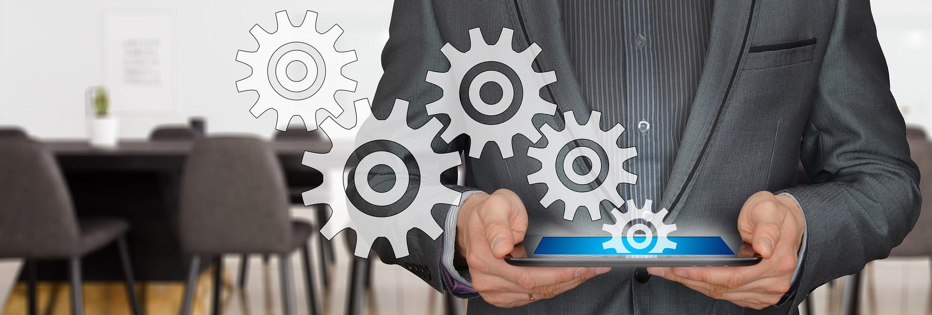 Professional holding tablet with gear icons, symbolizing strategic business planning.